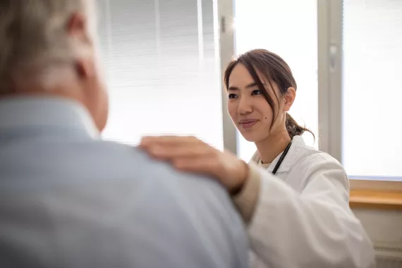 Doctor giving support to her male senior patient